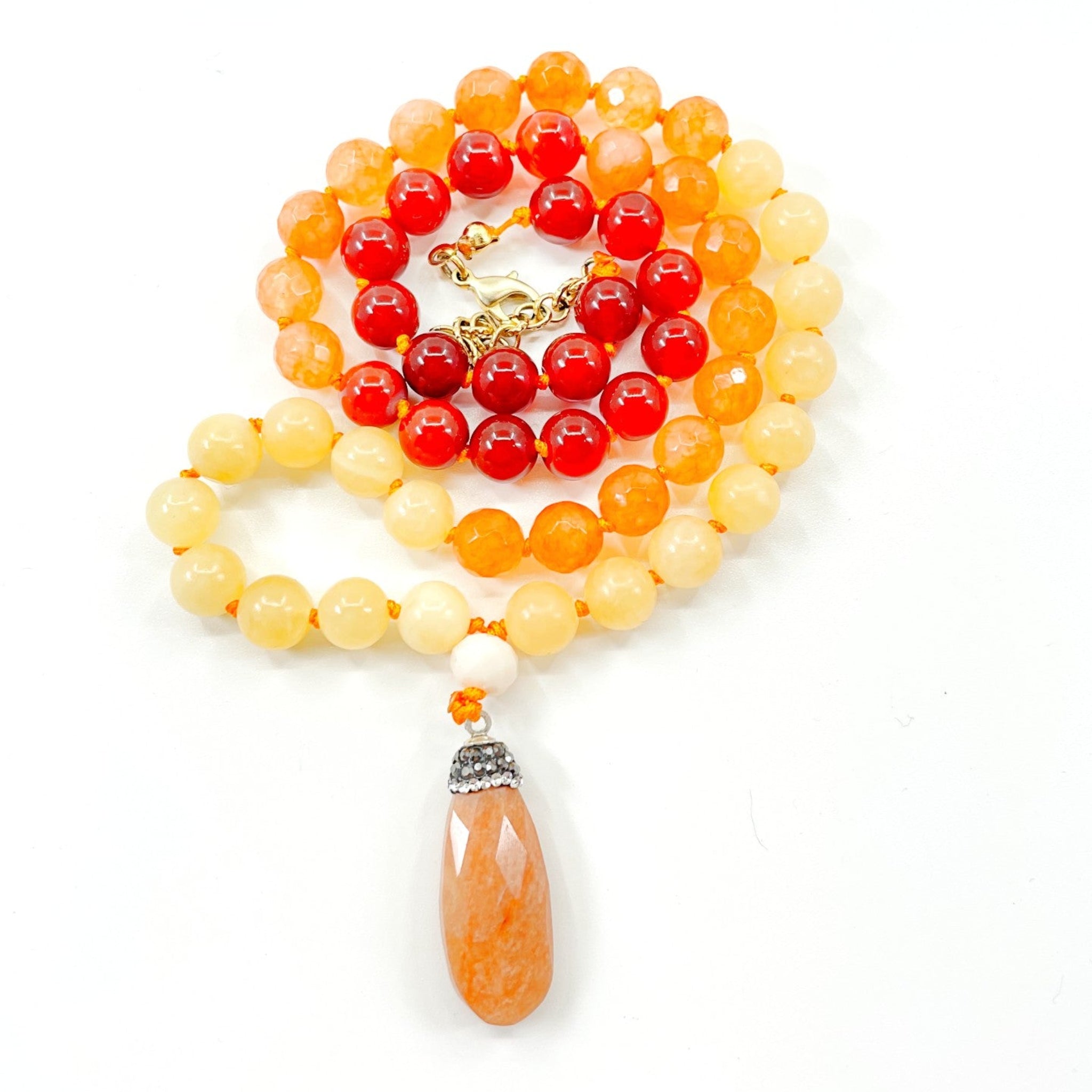 A colorful half mala necklace with a combination of orange, red, and clear beads, finished with a sunstone pendant.