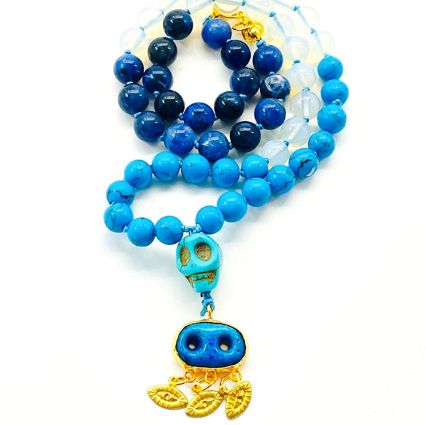 A beaded necklace with a mix of blue and clear beads, featuring a central Assyrian Evil Eye Pendant and a symbol of intuition.
