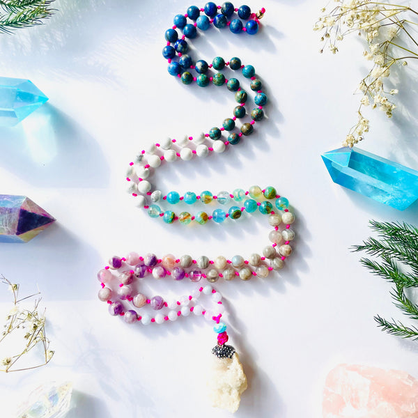 colorful gems beaded with geode pendant on white surface with blue and purple crystals and flowers