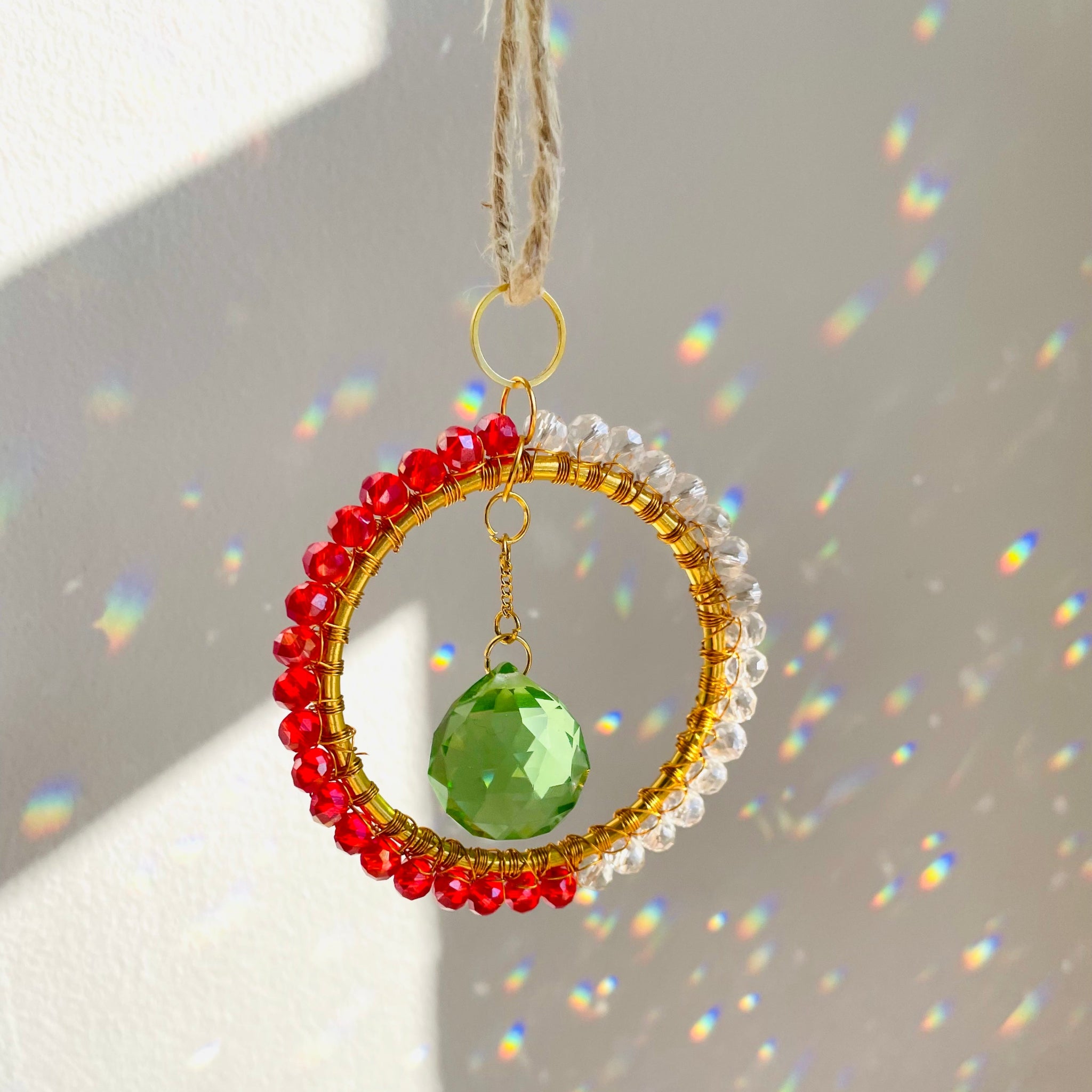 A mini circle suncatcher with a golden frame and clear crystal pendants hung from a chain.