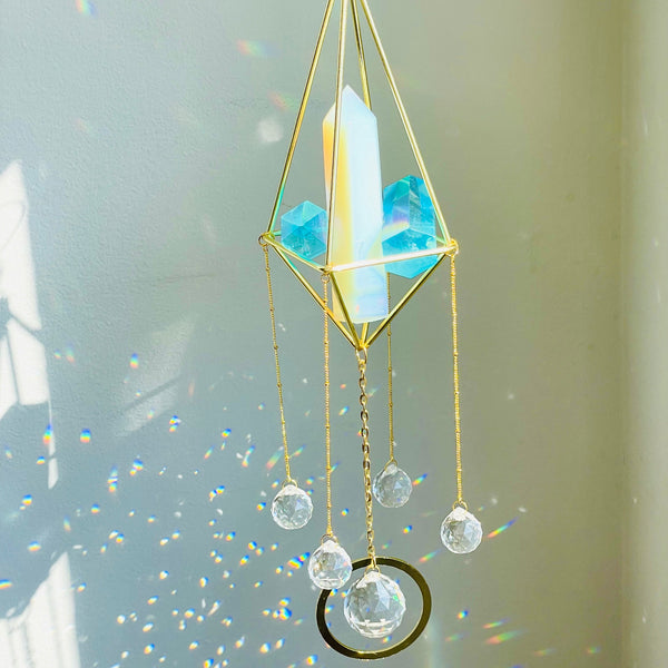 A geometric-shaped suncatcher with opal tower and blue angel aura quartz mini towers, adorned with glass crystal prisms, suspended by a rope.