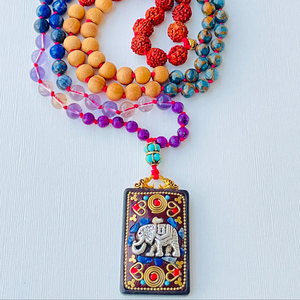 colorful beaded necklace with elephant pendant on white surface