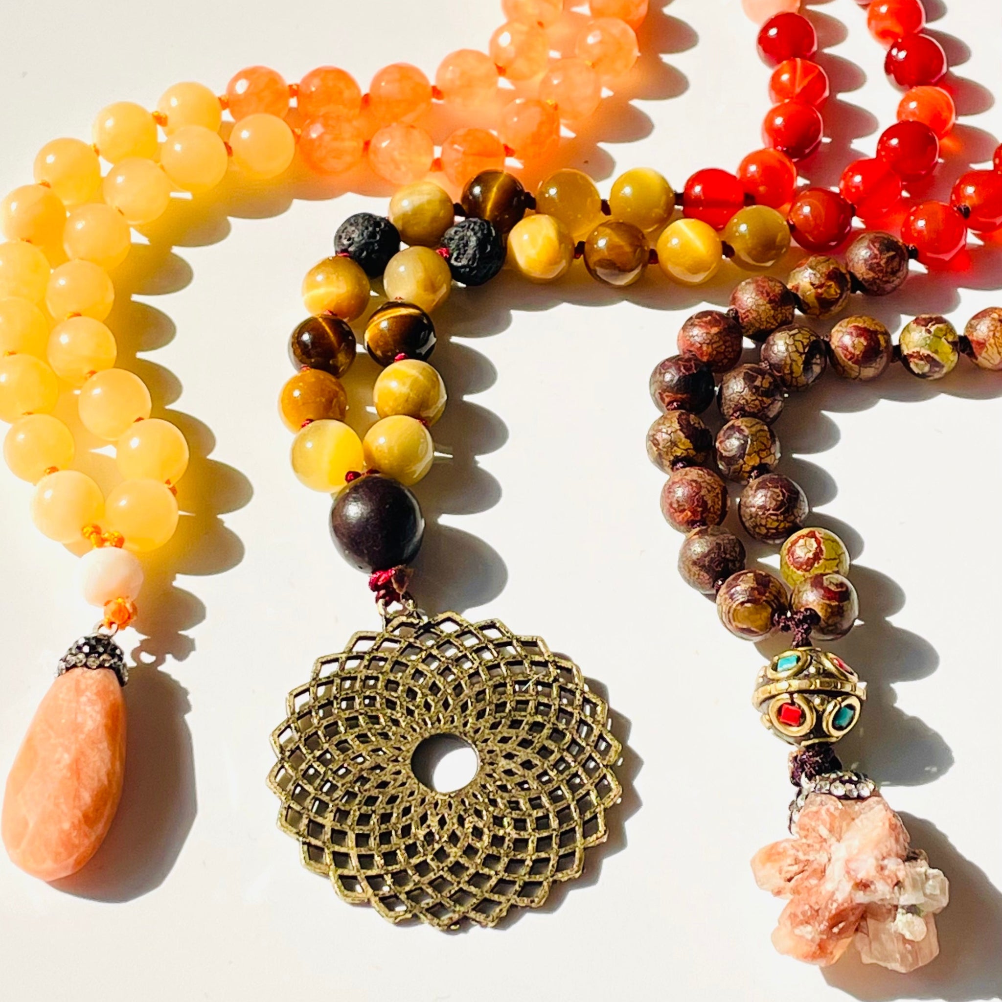 Three beaded necklaces with decorative pendants on a light background