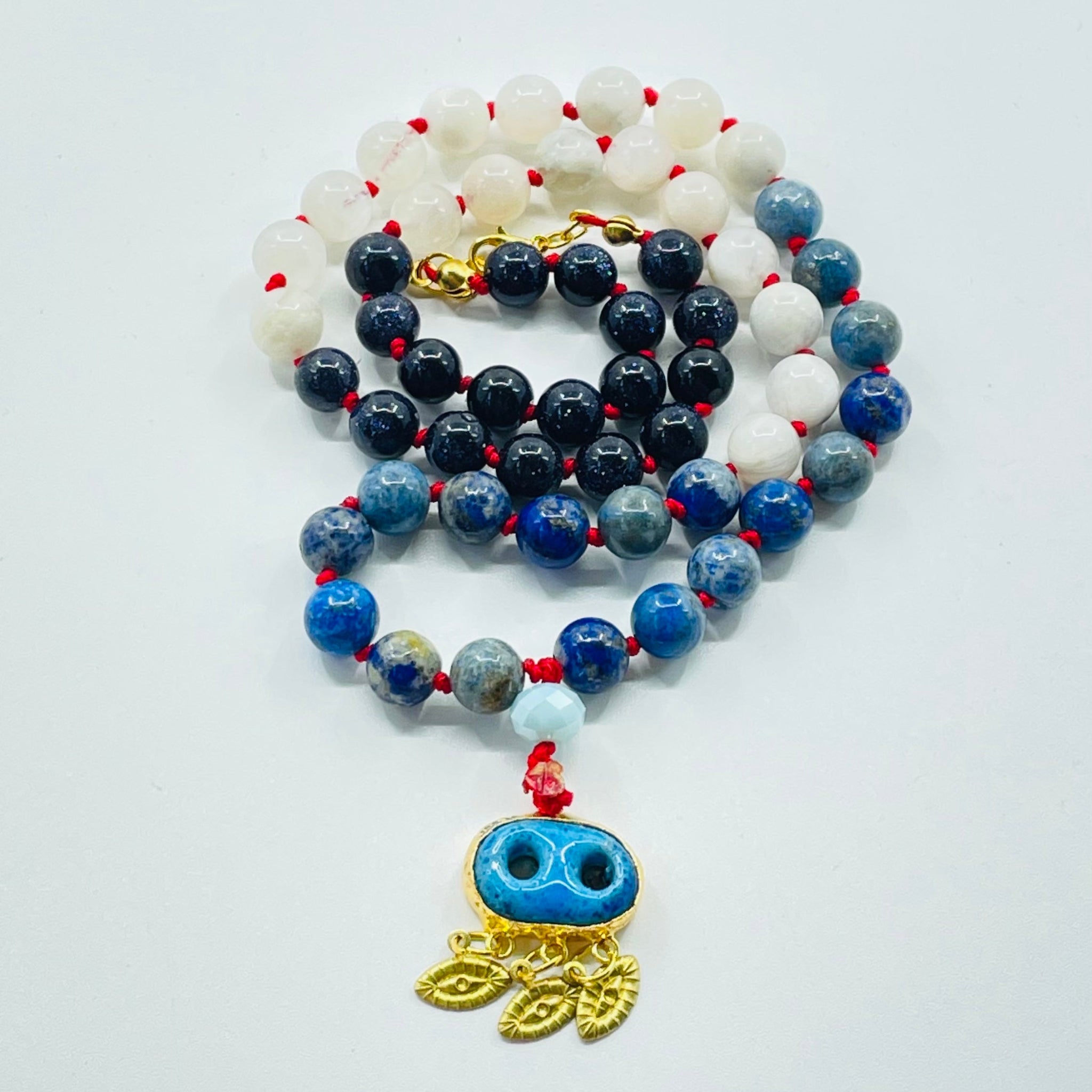 Beaded blue and beads with evil eye pendant on white surface