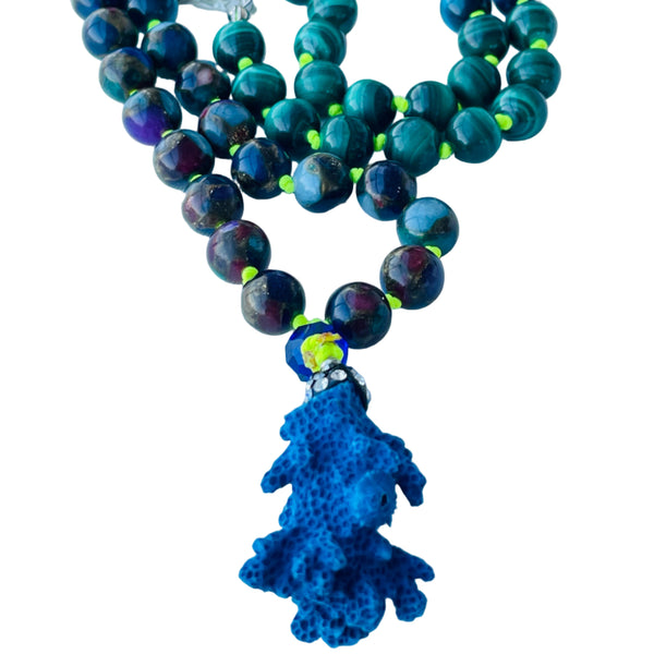 A beaded necklace with a mix of blue and green gemstone beads, a coral pendant, and a silver cap on the bottom bead.