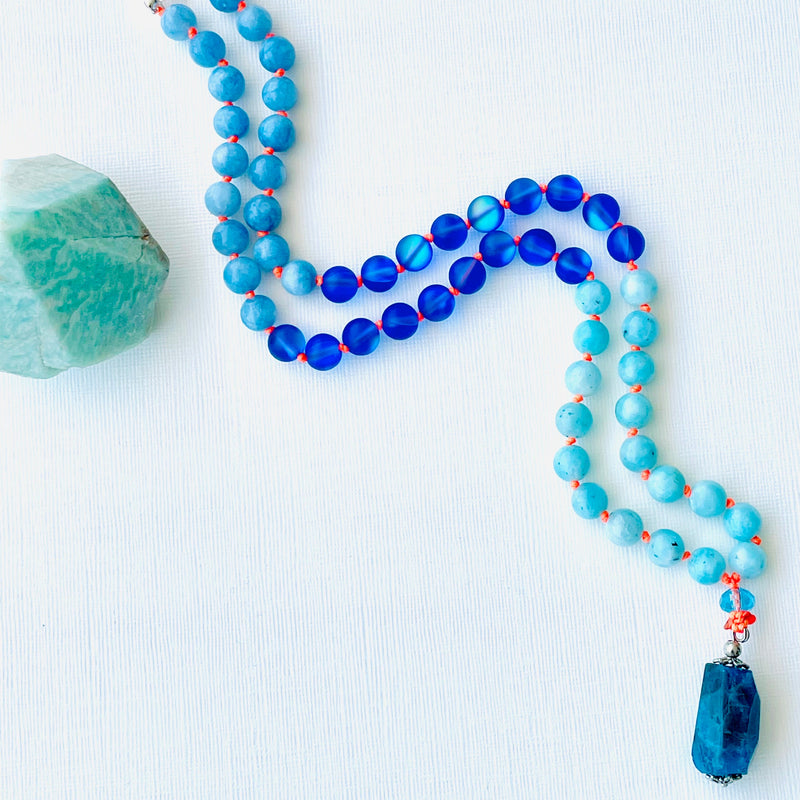 beaded blue gemstones with blue crystal on white surface