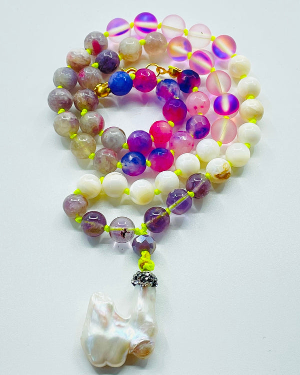 beaded white and pink gemstones with pearl pendant on white surface